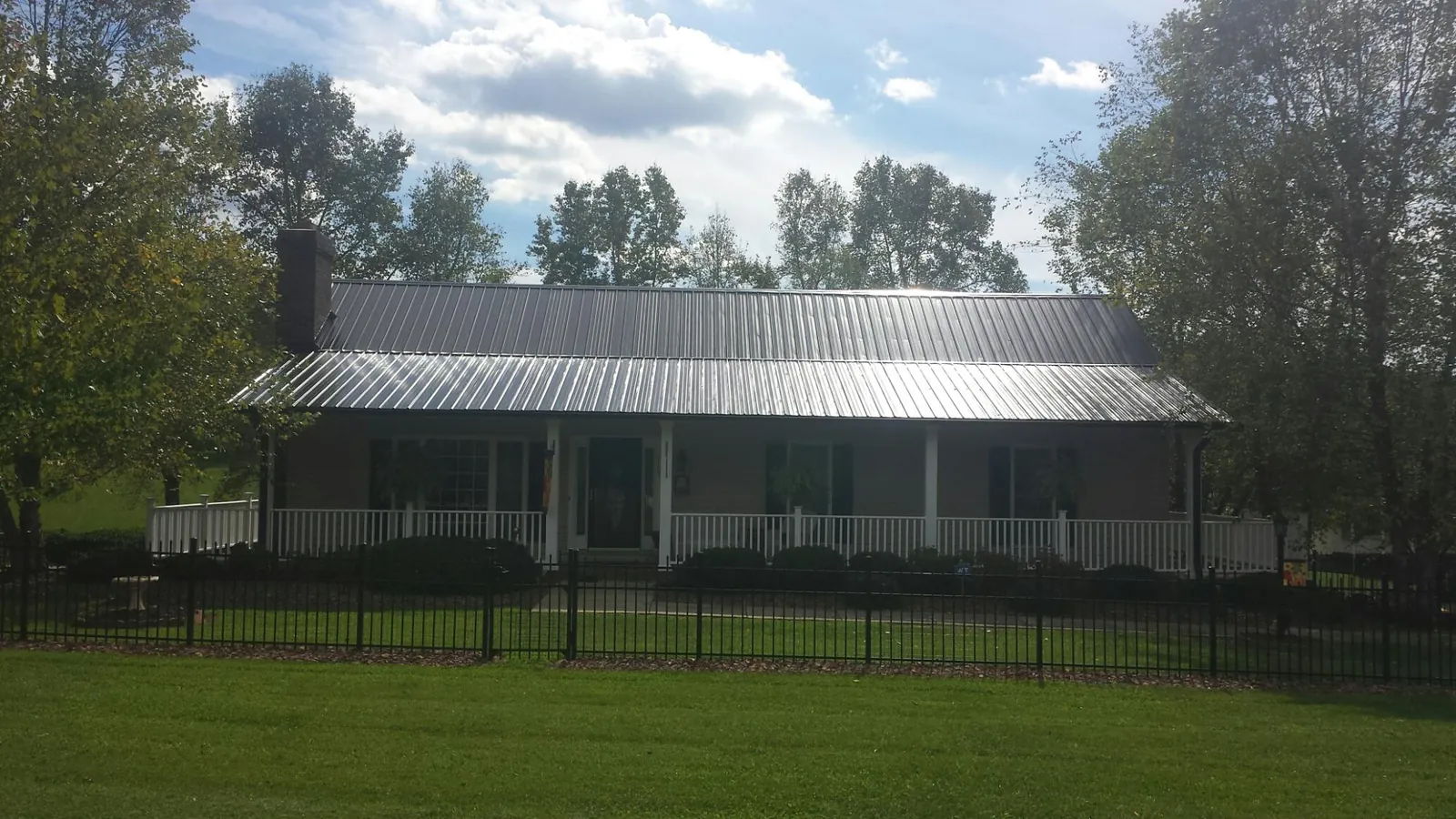 Gray metal roof on a brick ranch with a full width front porch — Gutter Guard Installation work by our crew in Kenilworth