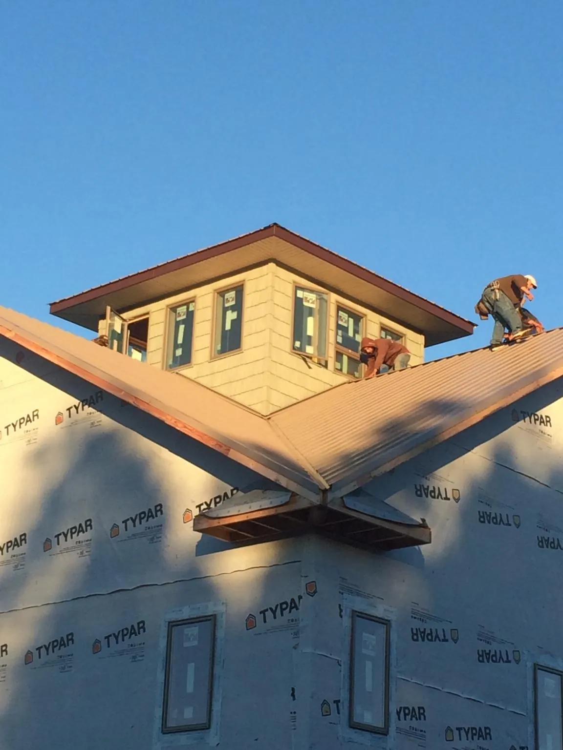 Roofers working around a rooftop cupola on a new metal roof at sunset — Roof Waterproofing in Kenilworth by Roofing Brothers